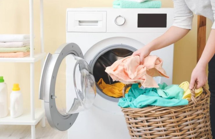 Persona mette il bucato in lavatrice