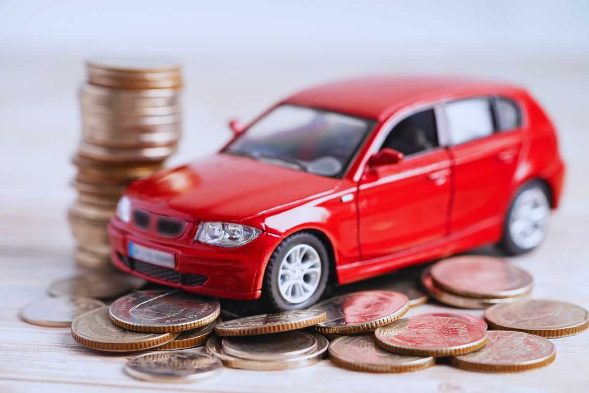 modellino auto e pila di monete poggiate su un tavolo