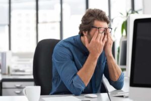 Uomo al pc con le mani sul viso