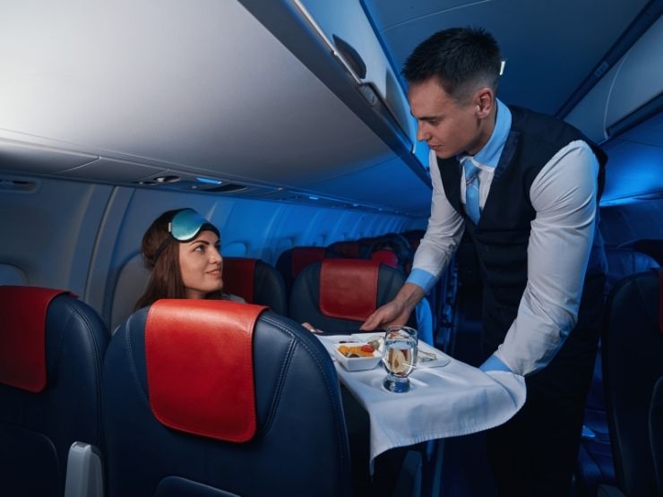assistente d'aereo che offre cibo a passeggera