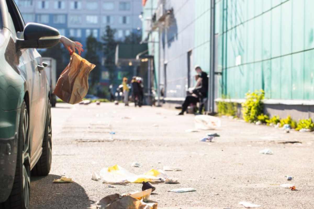 persona getta sacchetto dal finestrino della sua auto