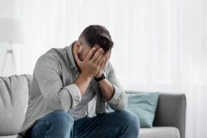 uomo che si nasconde il volto con le mani