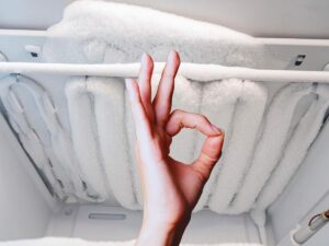 freezer con ghiaccio e mano che fa ok