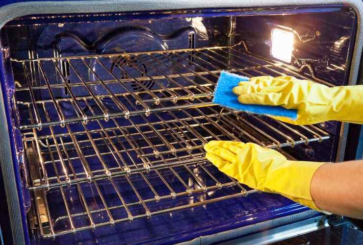 donna pulisce forno pieno di grasso