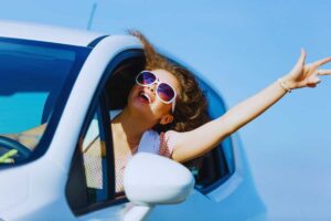 Donna felice che si sporge dal finestrino dell'auto