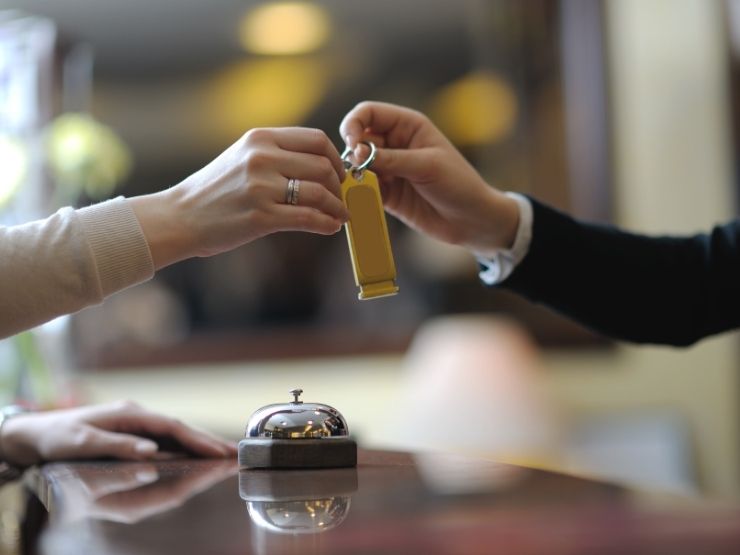 uomo che lavora in albergo che consegna chiavi