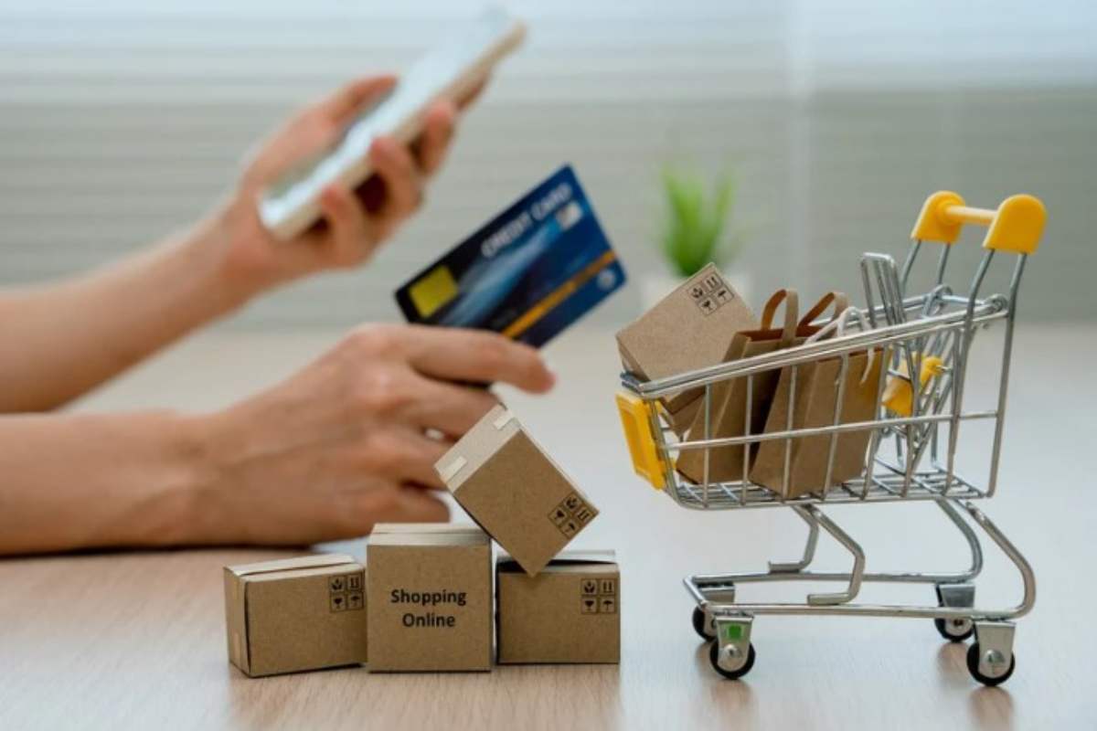 persona effettua acquisti online dal telefono con la carta , nell'immagine un carrello con diversi scatoloni