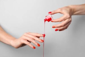 Donna con smalto rosso si versa il prodotto sulle mani