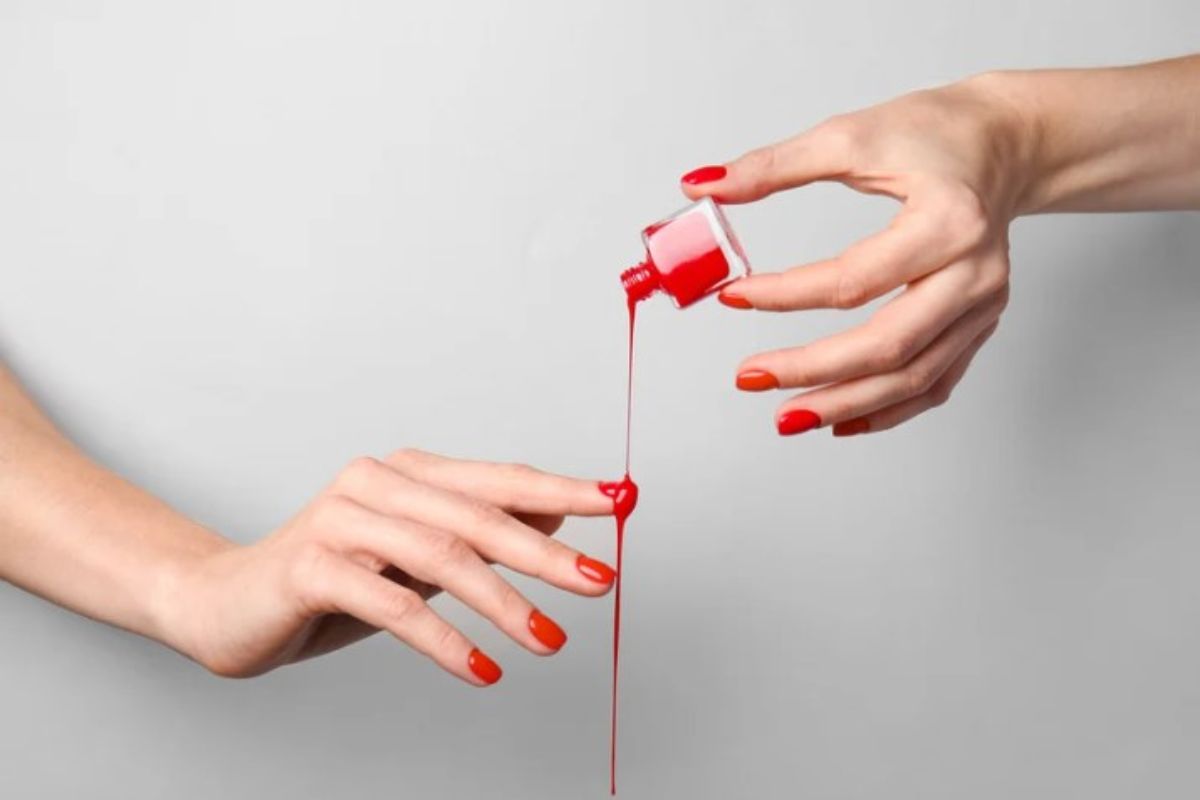 Donna con smalto rosso si versa il prodotto sulle mani