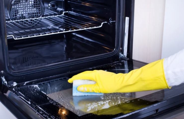 Persona pulisce il vetro del forno 