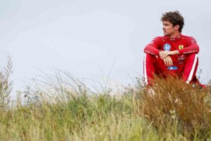 Leclerc seduto sul prato attorno alla pista con espressione sconfortata
