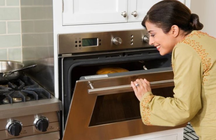 donna apre il forno per controllare la cottura 