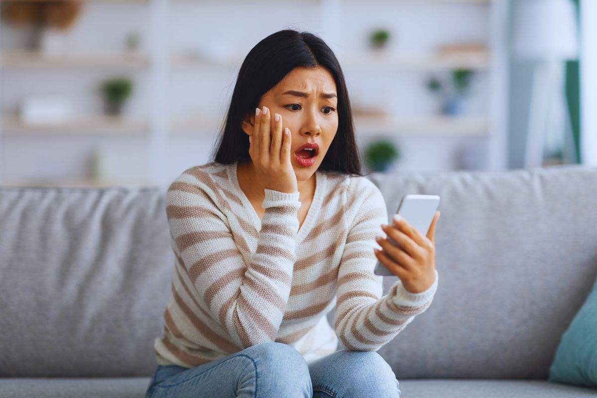 ragazza sbalordita mentre osserva smartphone