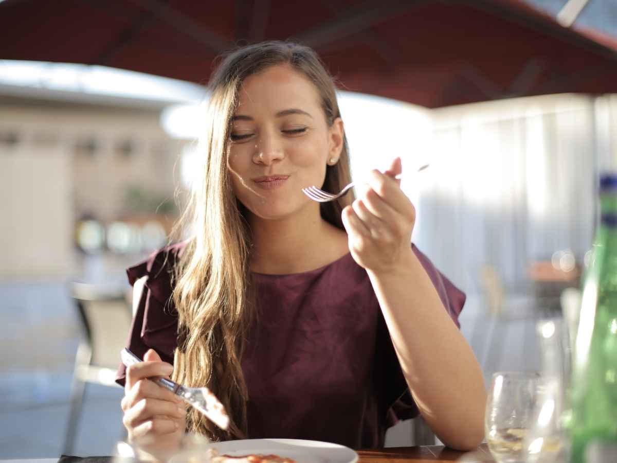 donna seduta al ristorante che mangia soddisfatta