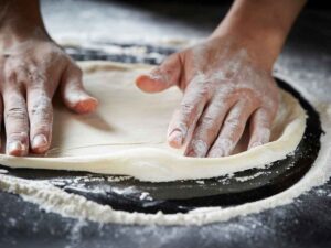 mani che stendono impasto pizza