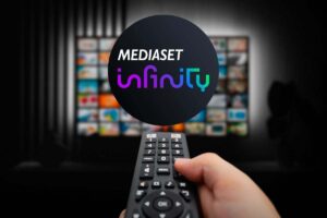 televisione con mano che tiene telecomando e nel cerchio il logo di mediaset