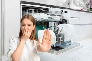 lavastoviglie e donna che si tappa naso