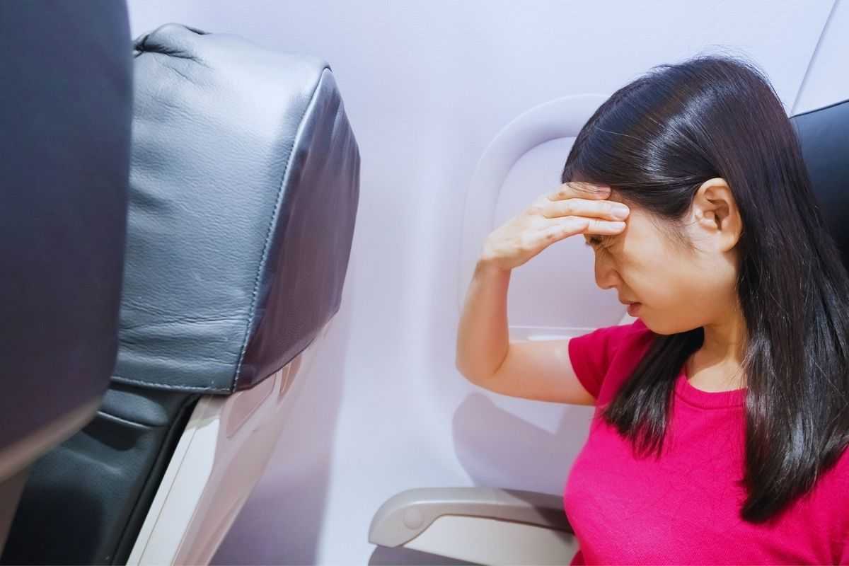 ragazza con mal di testa in aereo 