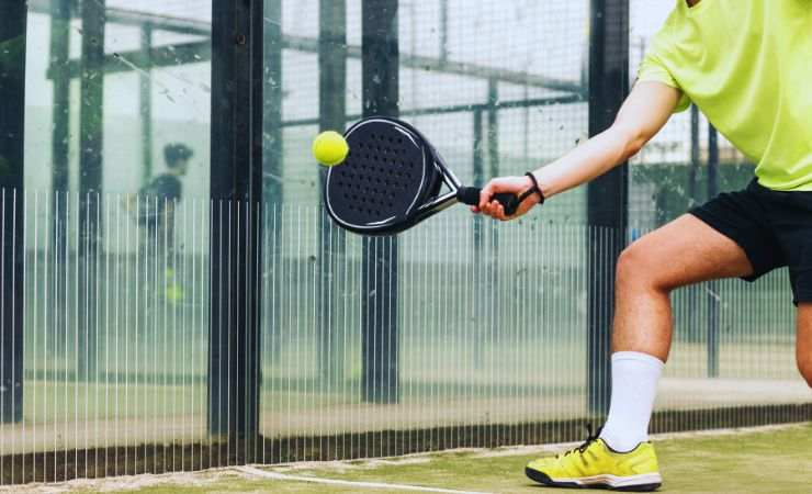 ragazzo colpisce la palla a padel