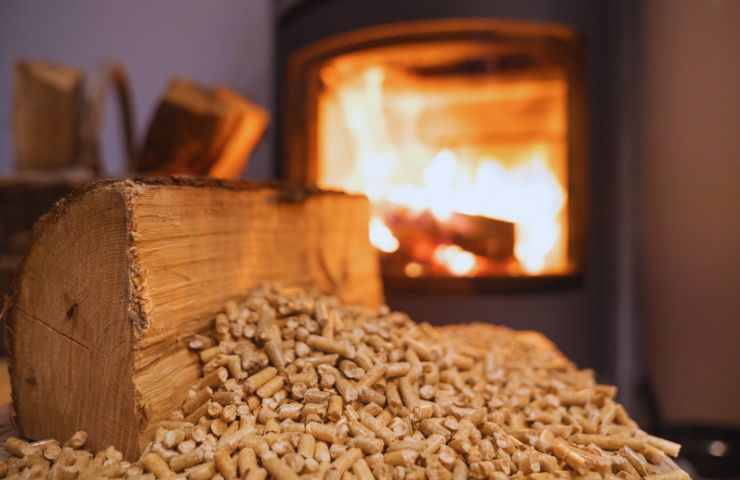 tronco di legno davanti al camino e pezzi di pellet