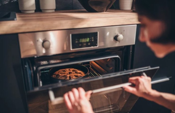 Donna controlla la cottura della torta nel forno 