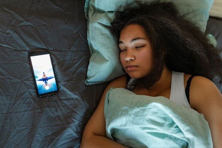 donna che dorme con telefono accanto