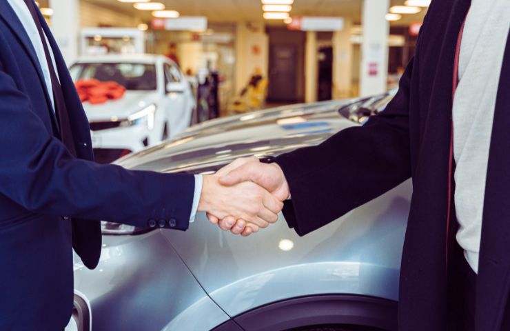 stretta di mano davanti a un'auto