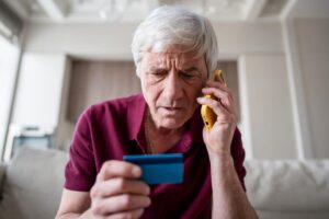 Anziano con carta, al telefono