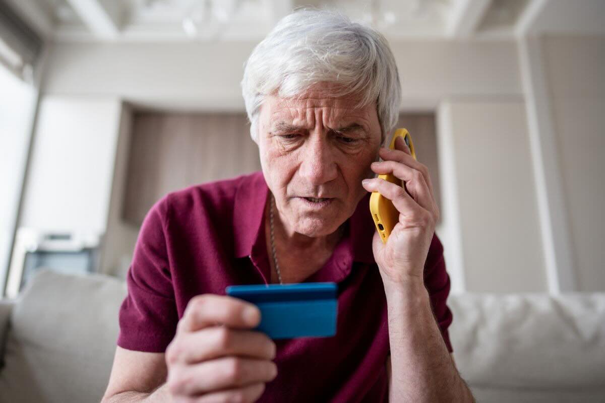 Anziano con carta, al telefono
