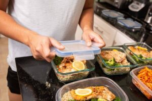Uomo riempie di cibo dei contenitori di plastica