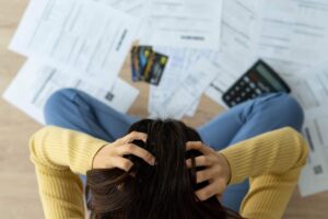 fogli, calcolatrice, donna con le mani nei capelli