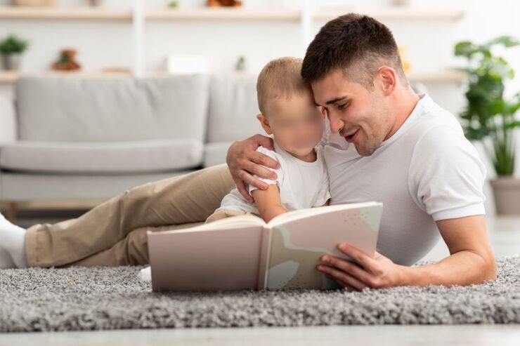 Ragazzo con bambino leggono libro sdraiati a terra