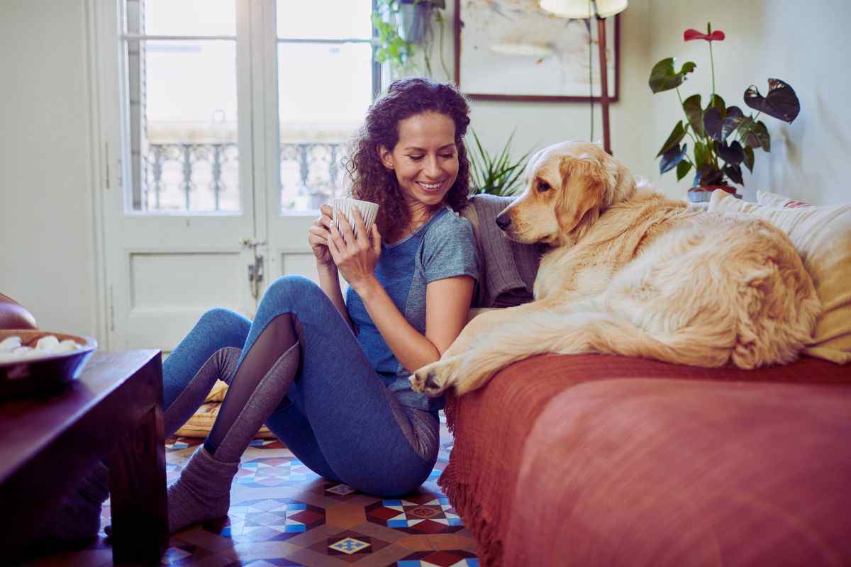 ragazza con una bevanda e cane sul divano