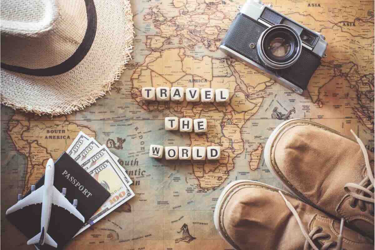 Cartina geografica, dadi con scritta, cappello, passaporto, scarpe, macchina fotografica