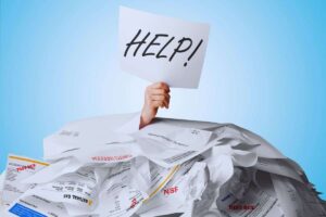 persona sommersa da fogli con cartello help