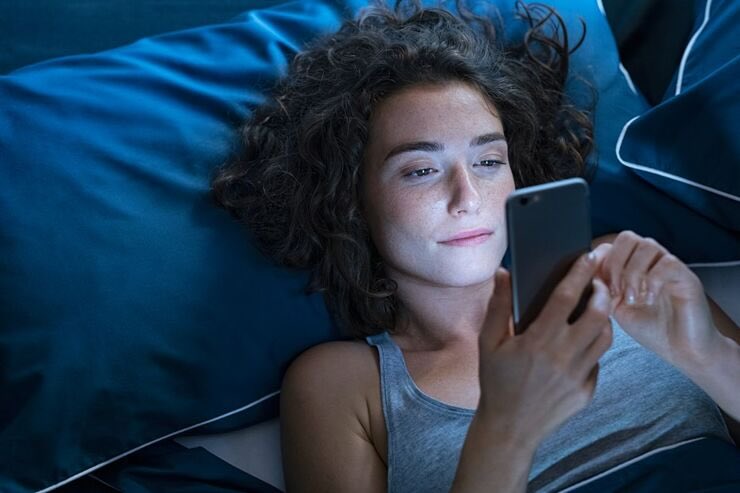 donna sul letto con telefono in mano