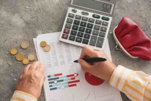 Scrivere su un foglio con grafici e conti, monete, calcolatrice