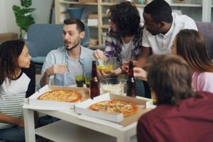 Amici mangiano pizza su un tavolino dai cartoni