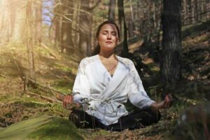 Donna seduta in meditazione nella foresta