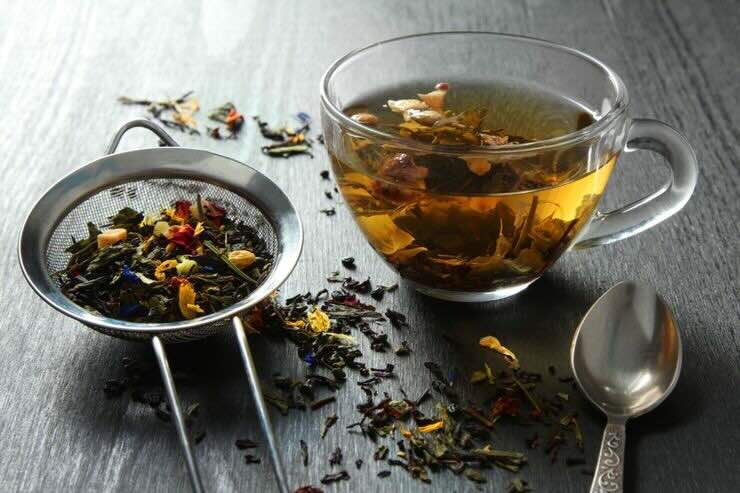 Foglie nel colino, tazza con tè 