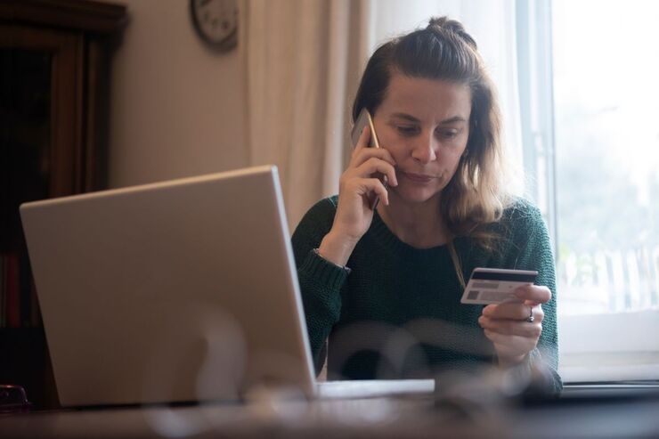 Donna con carta, al telefono, e PC