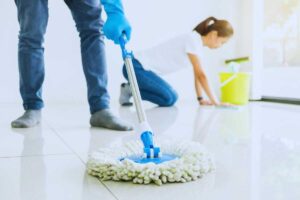 persona pulisce pavimento col mocio